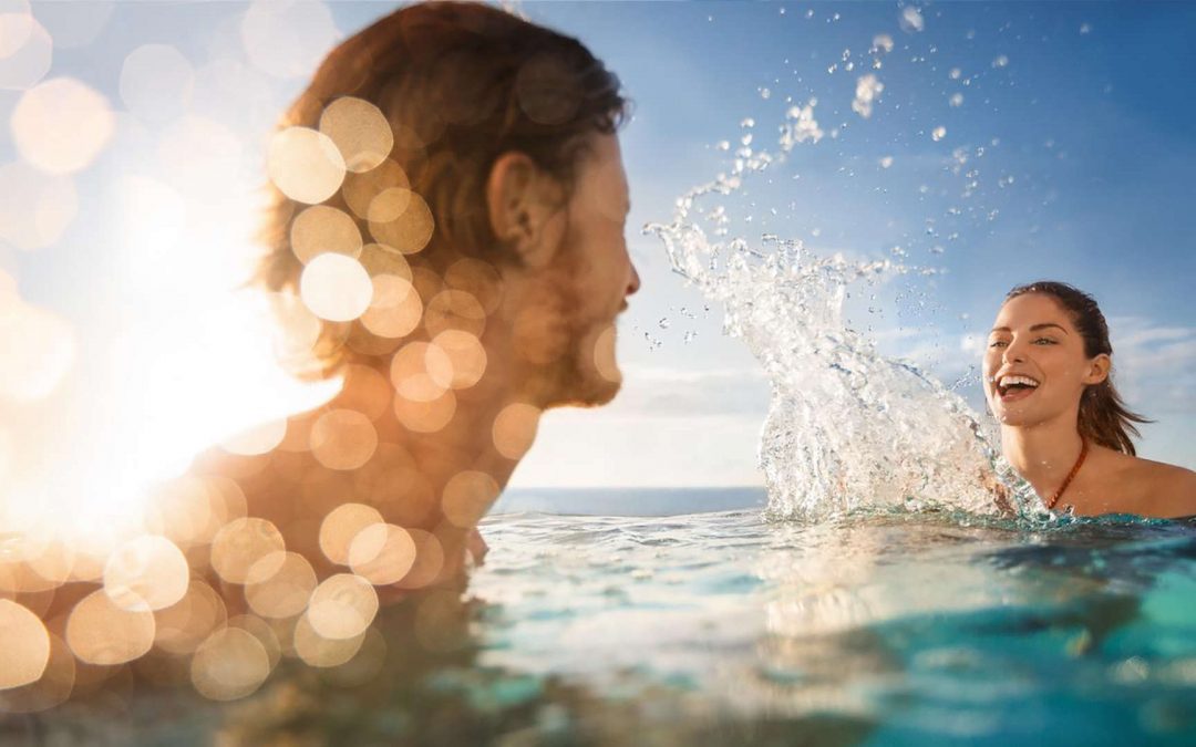 Gäste baden im Pool auf einem AIDA Kreuzfahrtschiff unter Sonnenschein